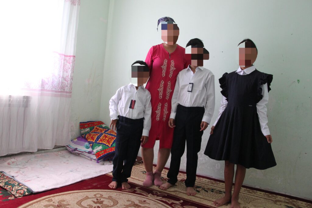 A mother and three children wearing new school uniforms